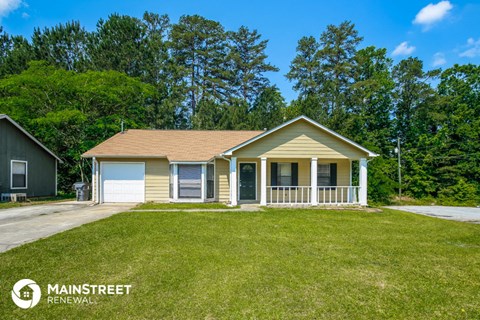 a small yellow house with a porch and a lawn