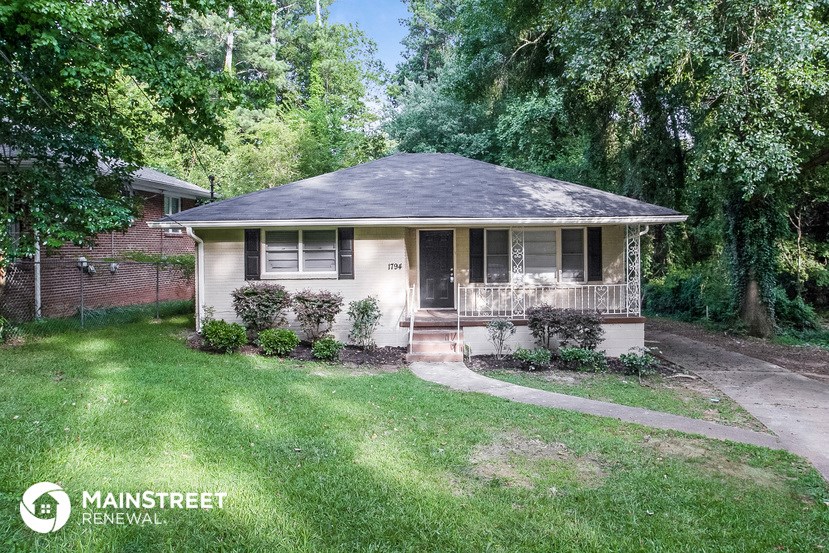 a small white house with a porch and a yard