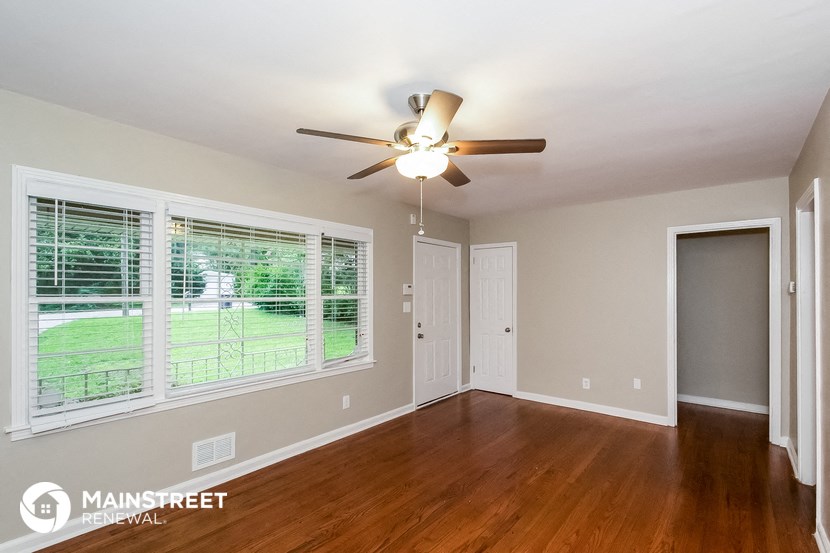 a living room with a large window and a ceiling fan