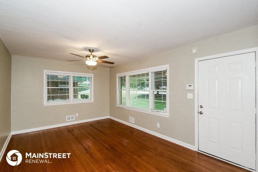 the living room of a home with wood floors and a ceiling fan