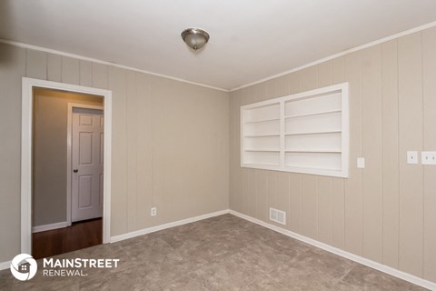 the living room of a home with a gray carpet and a white window and shelf