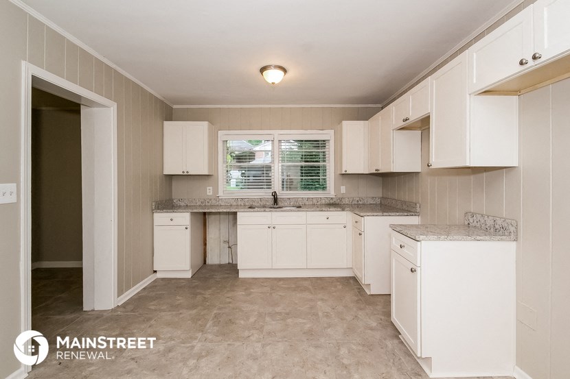 a white kitchen with white cabinets and a window