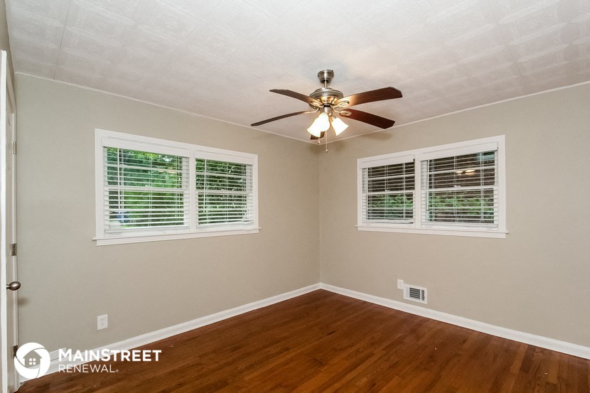 the bedroom has a ceiling fan and two windows
