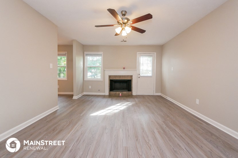 the spacious living room with fireplace and ceiling fan