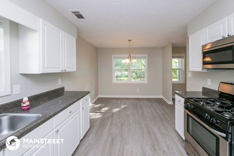 a kitchen and living room with white cabinets and stainless steel appliances