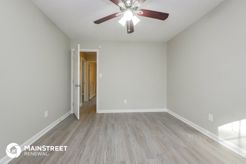the spacious living room with wood flooring and a ceiling fan