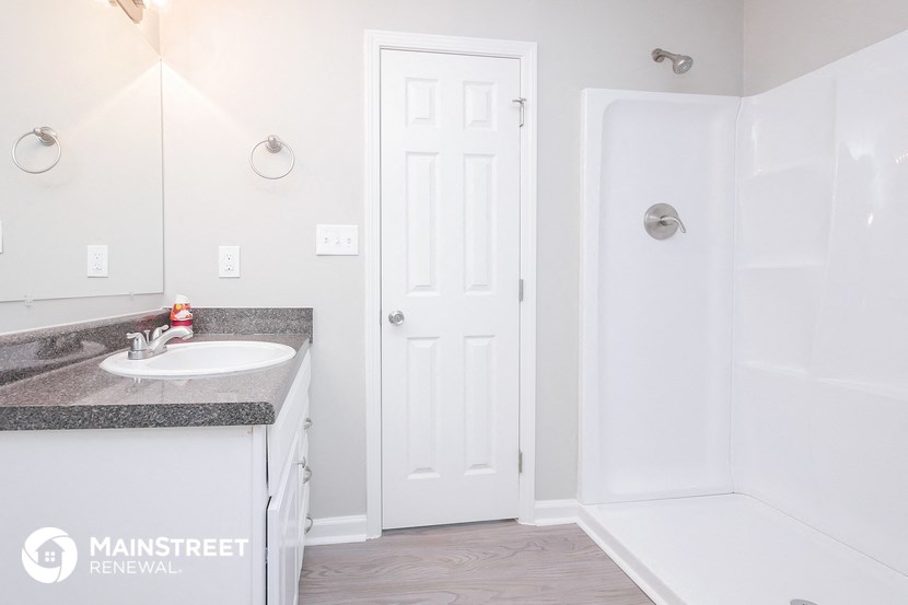 a bathroom with a sink and a shower and a white door