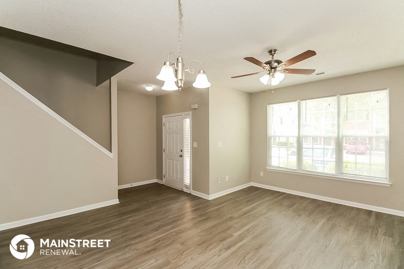 an empty living room with a ceiling fan and a window