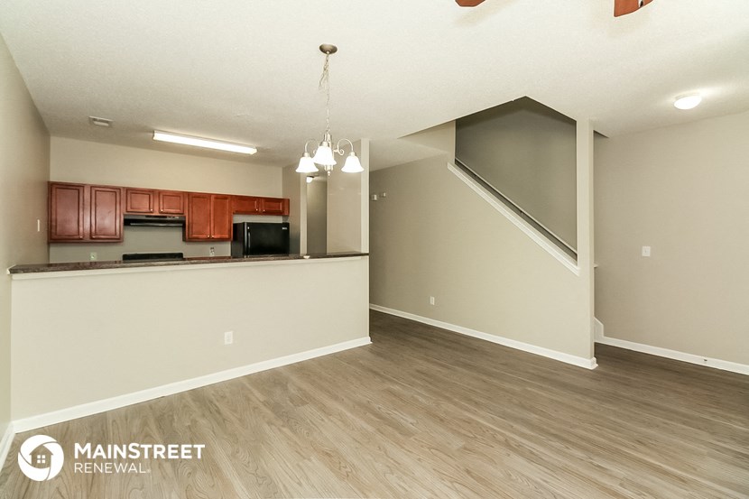 the living room and kitchen of an apartment with wood flooring