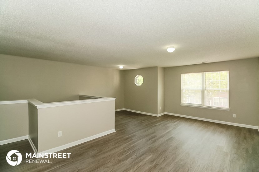 the spacious living room with hardwood flooring and a window