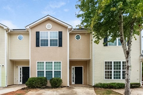 a beige house with a tree in front of it