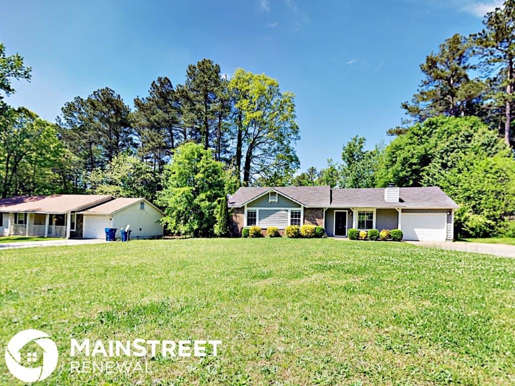 a house on a large lawn with trees in the background