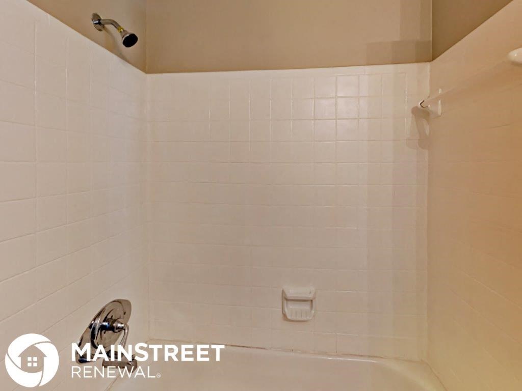 a white tiled bathroom with a shower and a sink