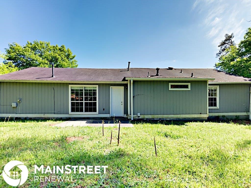 the front of a green house with a yard and grass
