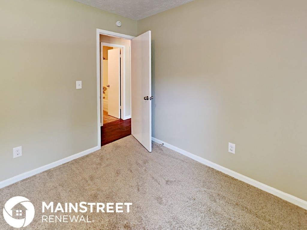 a bedroom with a carpeted floor and a door to a hallway