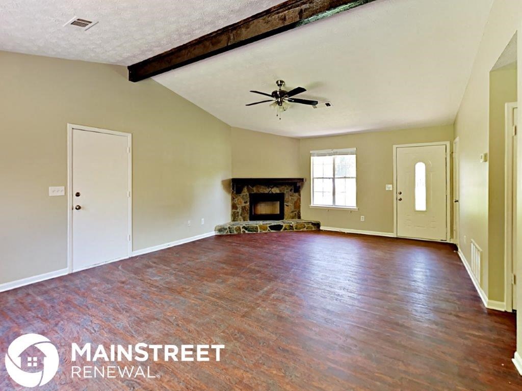 an empty living room with a fireplace and a ceiling fan