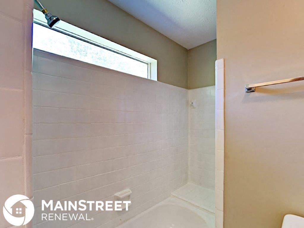 a bathroom with a shower and a toilet and a window