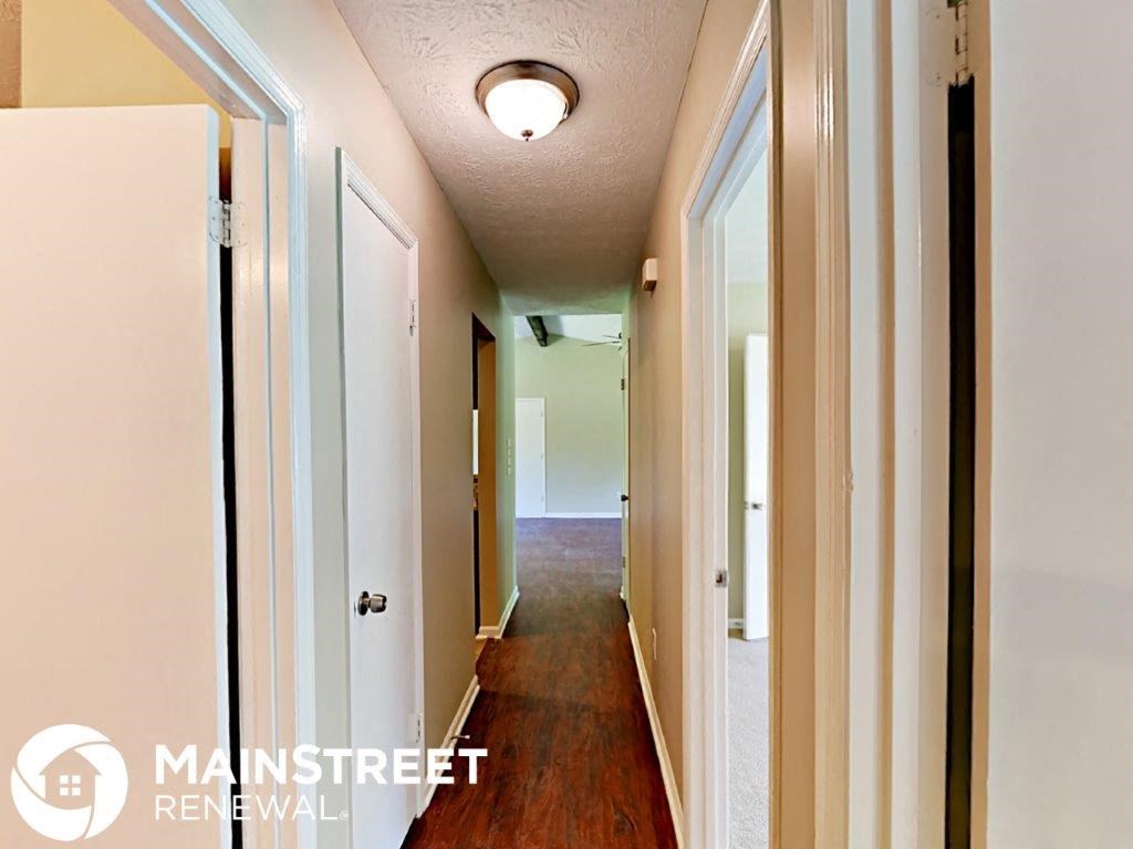 a long hallway with a door open to a bedroom and a closet