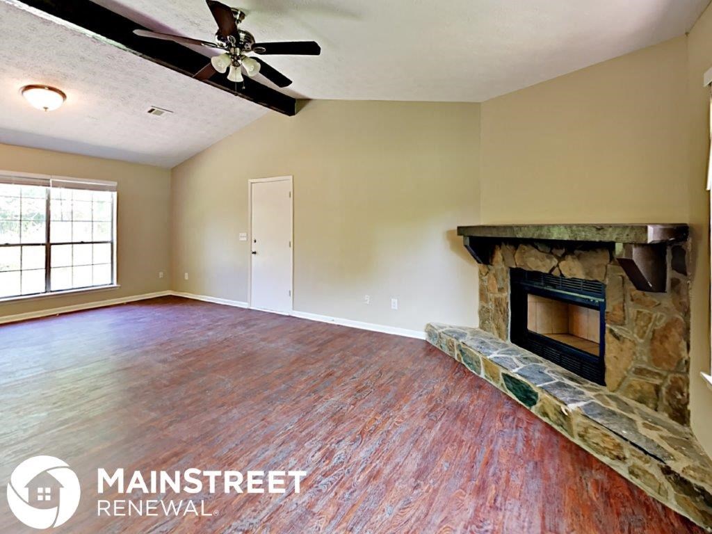 a living room with a fireplace and a ceiling fan