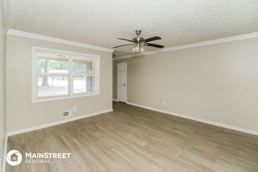 the living room of a house with wooden floors and a ceiling fan