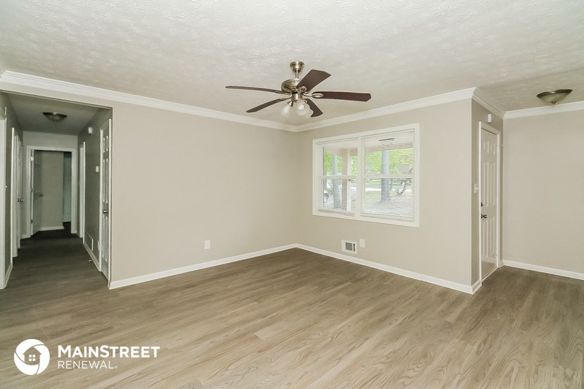 the living room of a house with wood floors and a ceiling fan