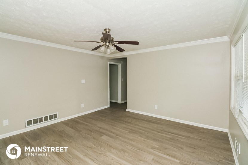 the spacious living room with ceiling fan and wood flooring