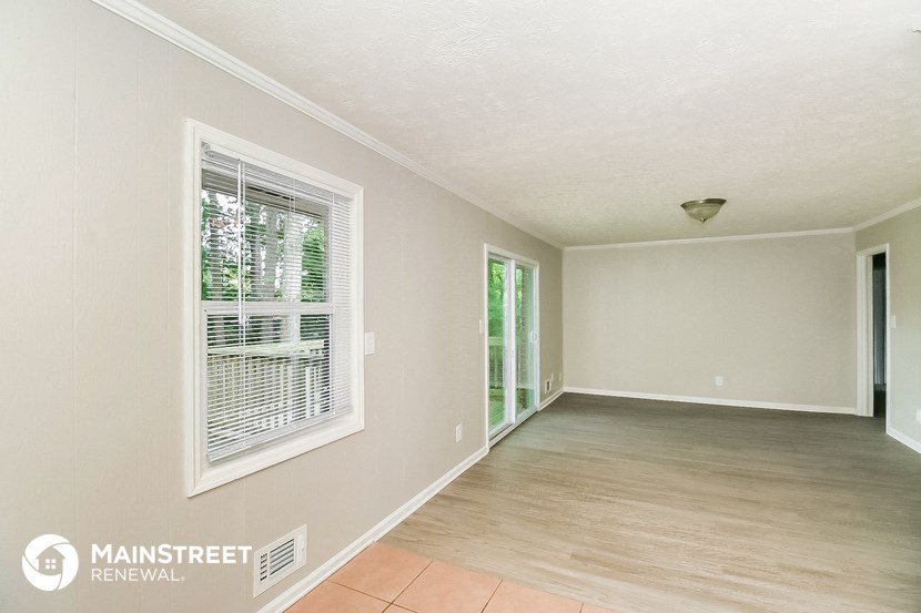 a spacious living room with a large window and wood flooring