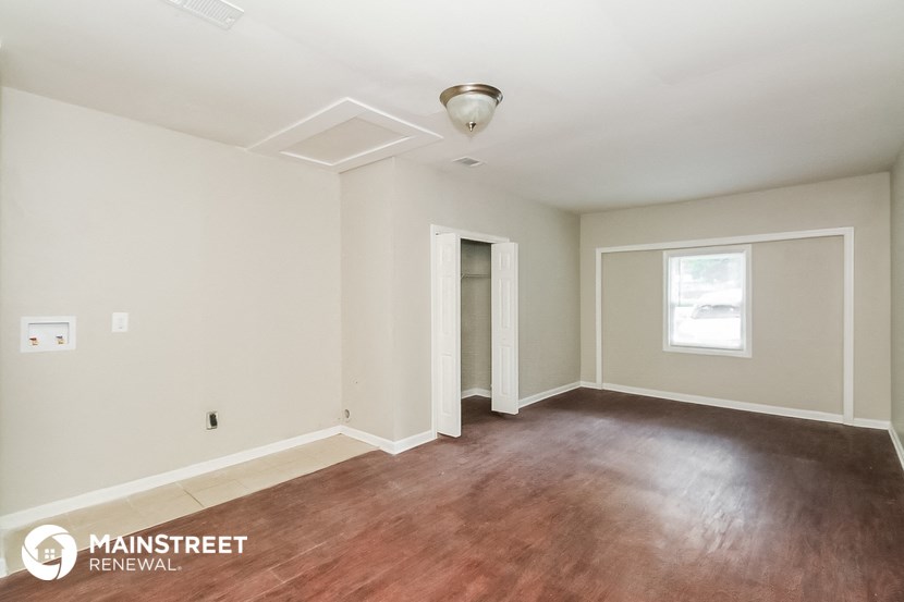 an empty living room with wood flooring and white walls