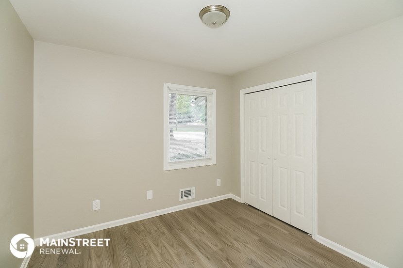the upstairs bedroom has a large window and hardwood flooring