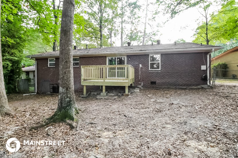 a house in the woods with a deck and a tree