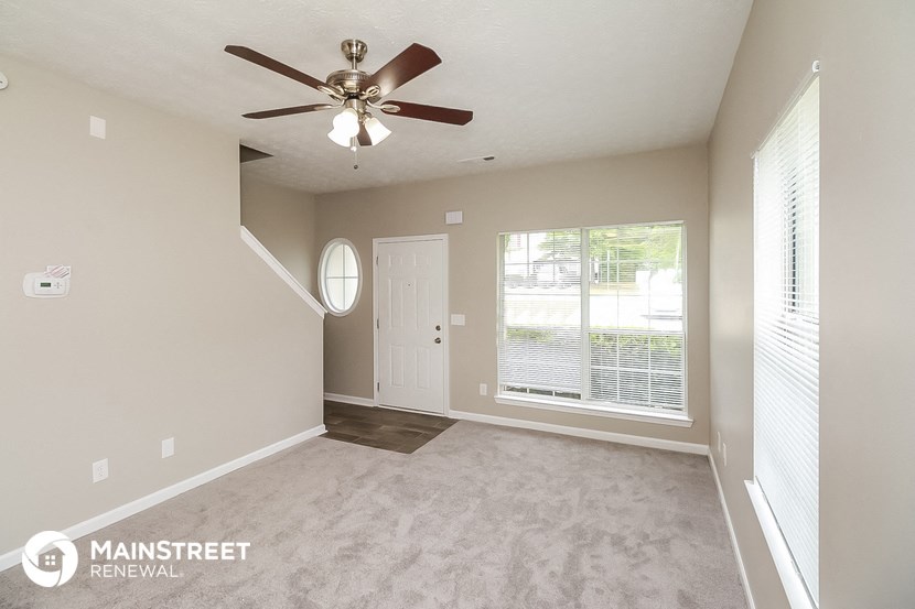 the spacious living room has a ceiling fan and a large window