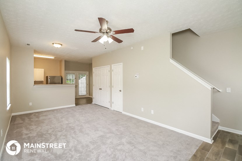 the spacious living room with ceiling fan and tile flooring