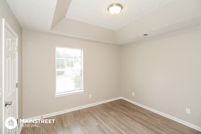 the spacious living room with hardwood flooring and a window