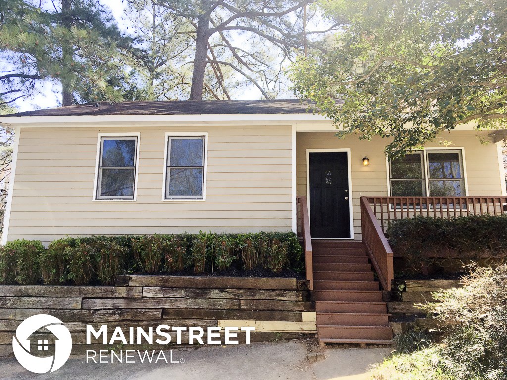 a small yellow house with stairs and a black door
