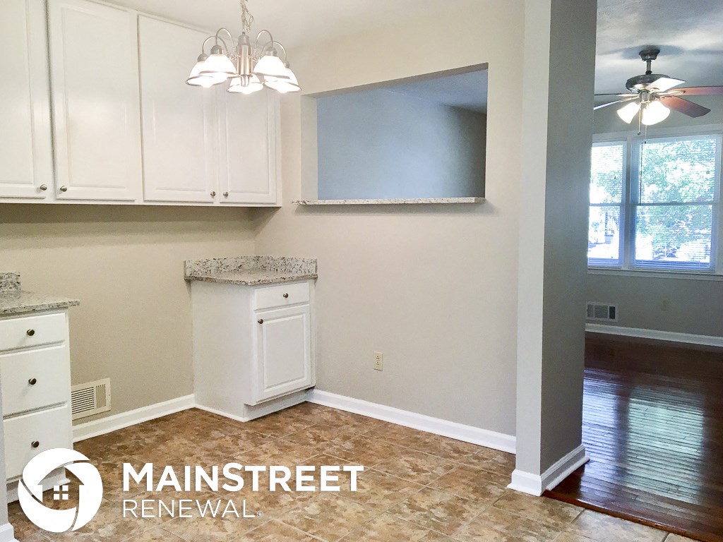 an empty kitchen with white cabinets and a window