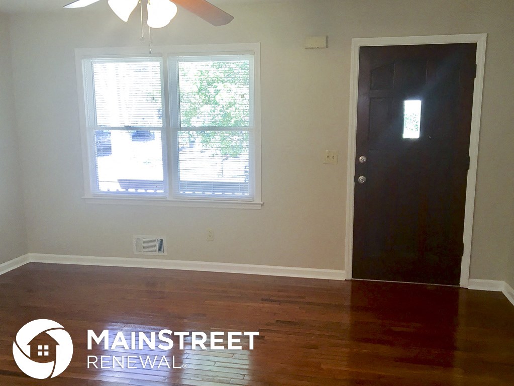 an empty room with wood floors and a window and a black door