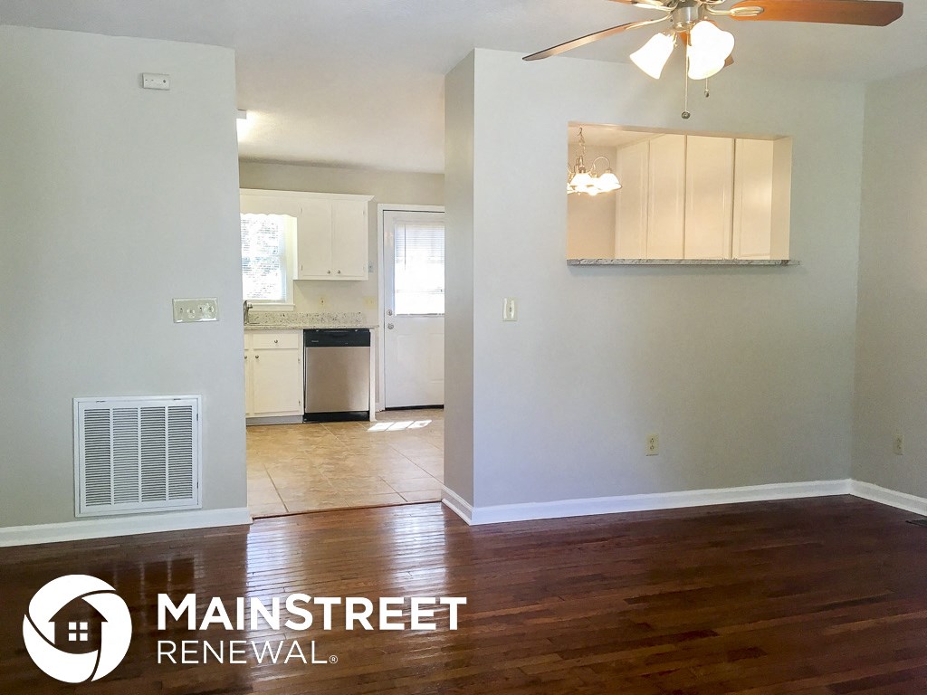 an empty living room and kitchen with wood floors and a ceiling fan
