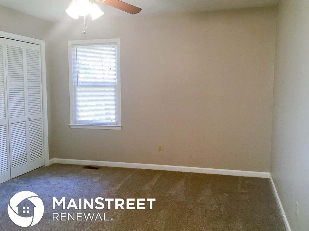 a room with a carpeted floor and a window and a ceiling fan