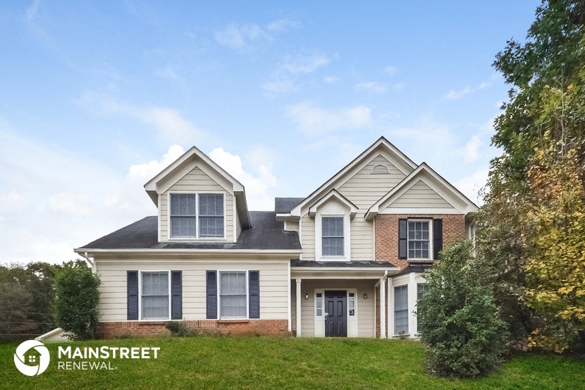 front view of a home with white siding and brick and a green lawn