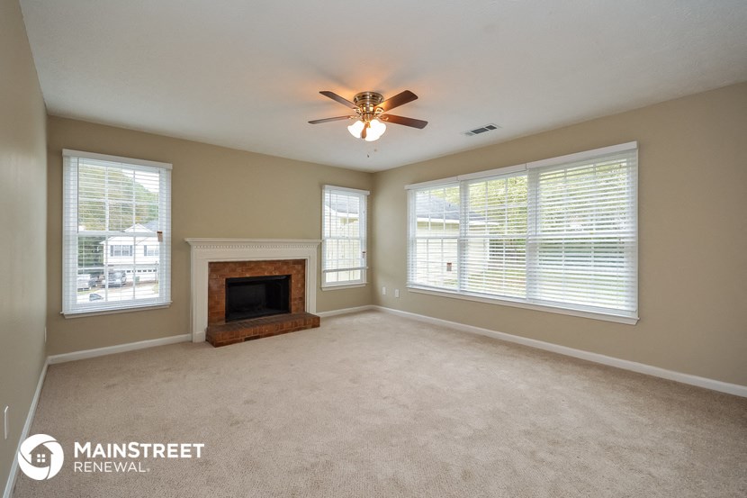an empty living room with a fireplace and a ceiling fan