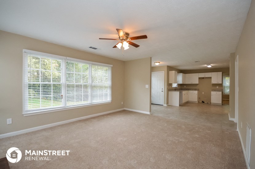 an empty living room with a ceiling fan and a large window