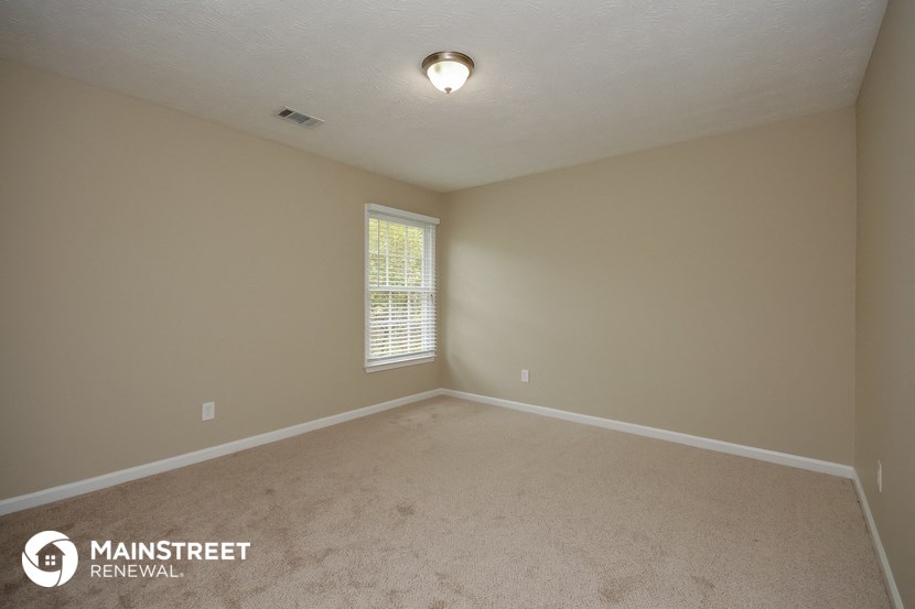 the interior of an empty room with carpet and a window