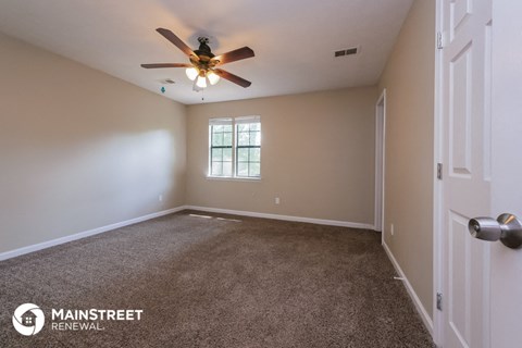 the spacious living room with carpet and ceiling fan