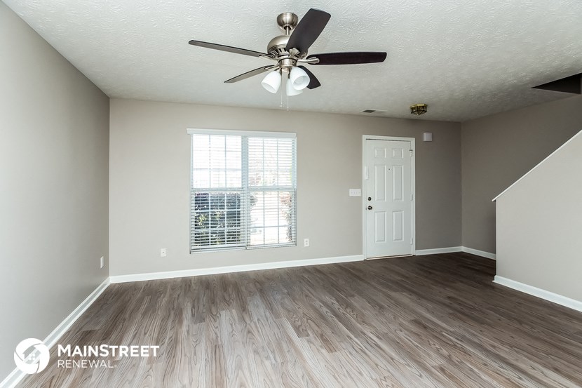 the living room of an empty house with a ceiling fan