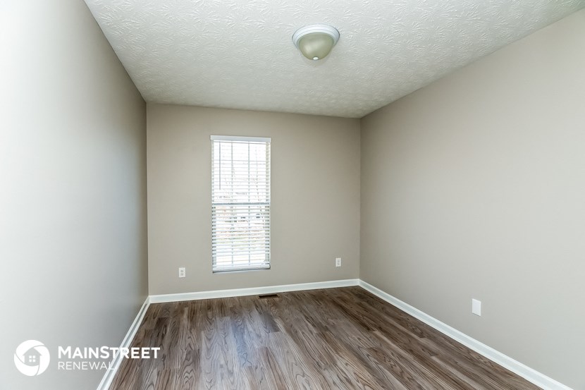 the spacious living room with hardwood flooring and window