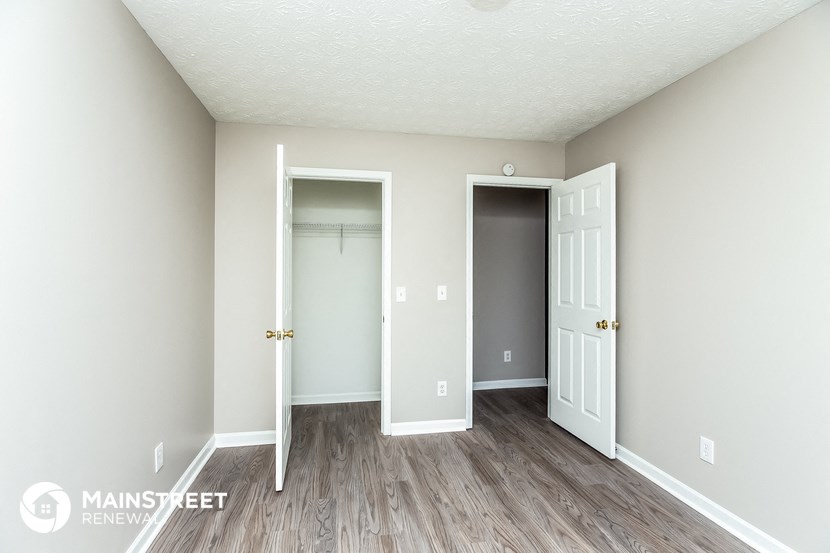 the living room of an apartment with wood floors and a closet