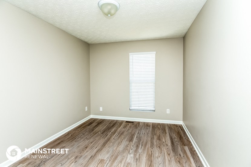 the spacious living room with wood flooring and white walls