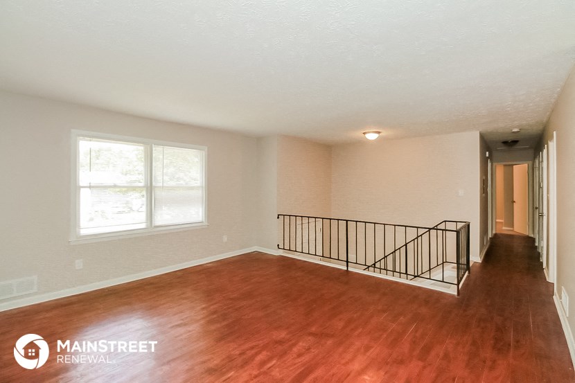 the living room of an empty house with wood flooring and a staircase