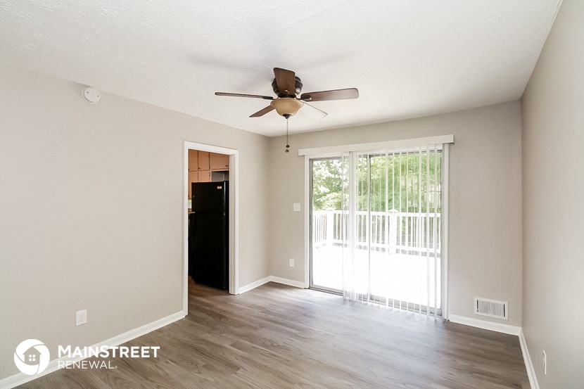 a living room with a ceiling fan and a door to a balcony