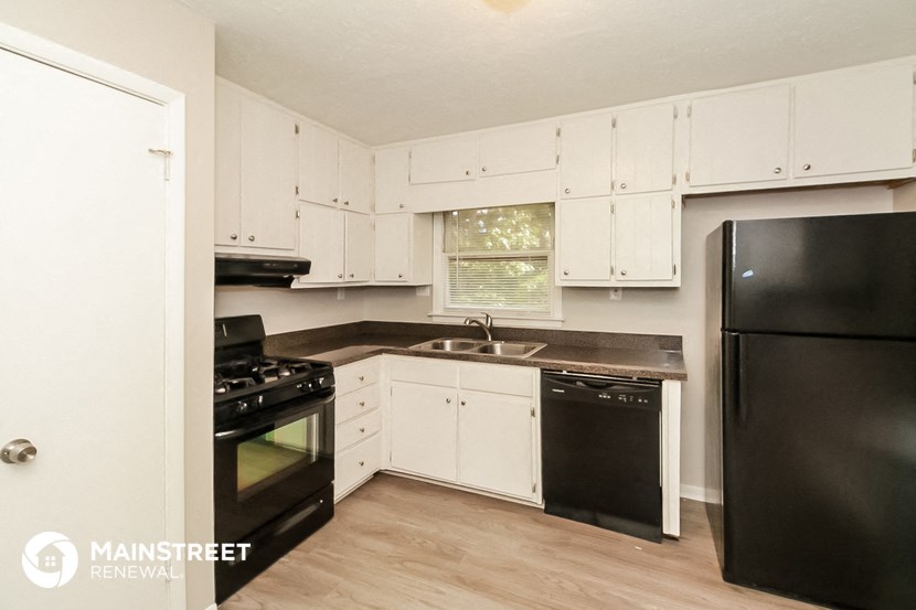 a kitchen with white cabinets and black appliances and a black refrigerator